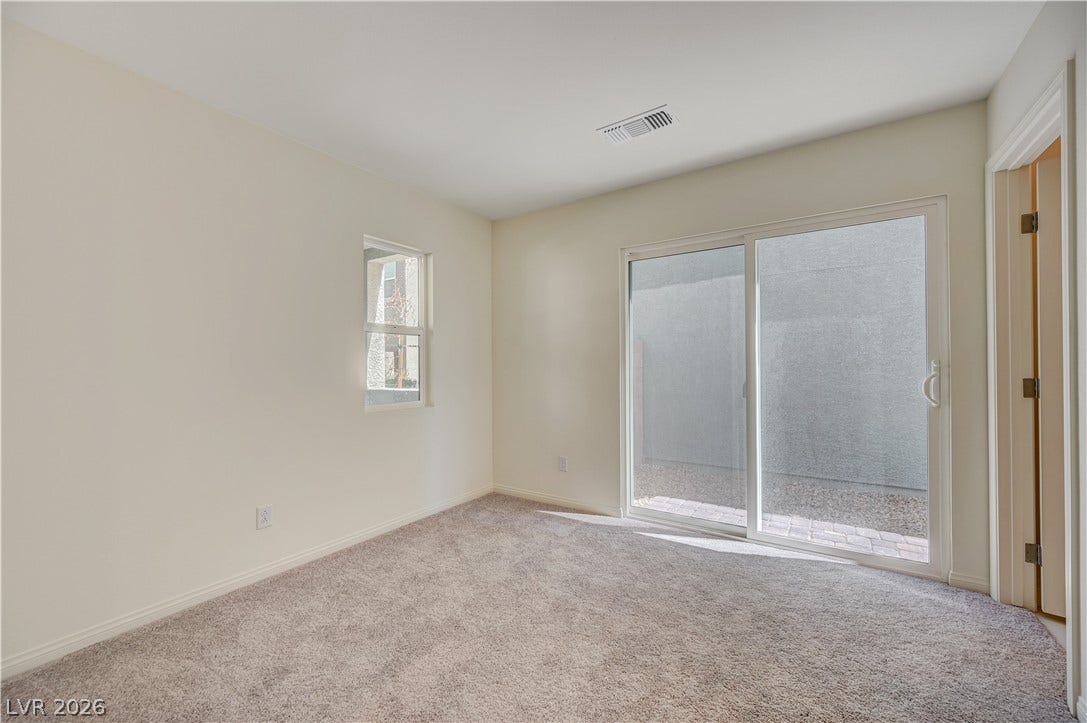 Glass sliding doors open to the outdoor patio from this carpeted secondary bedroom.