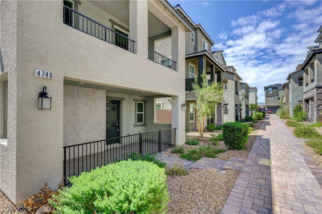 Multi-level modern stucco exteriors line a paved pedestrian pathway with desert landscaping.