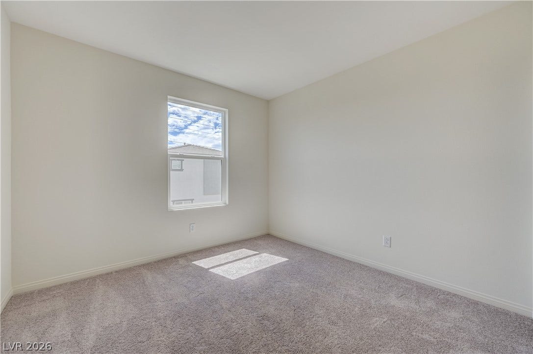 Natural light fills a serene secondary bedroom featuring plush carpet and a single window.