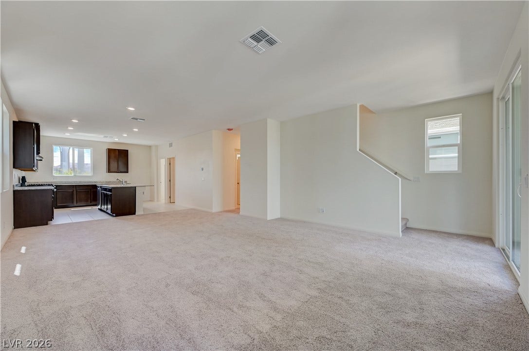An open floorplan seamlessly connects the carpeted living area to the kitchen.