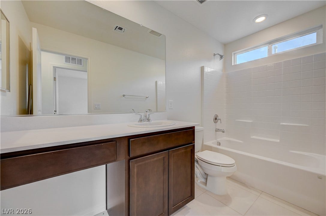 A classic tiled shower and tub combination sits adjacent to a dark wood vanity.