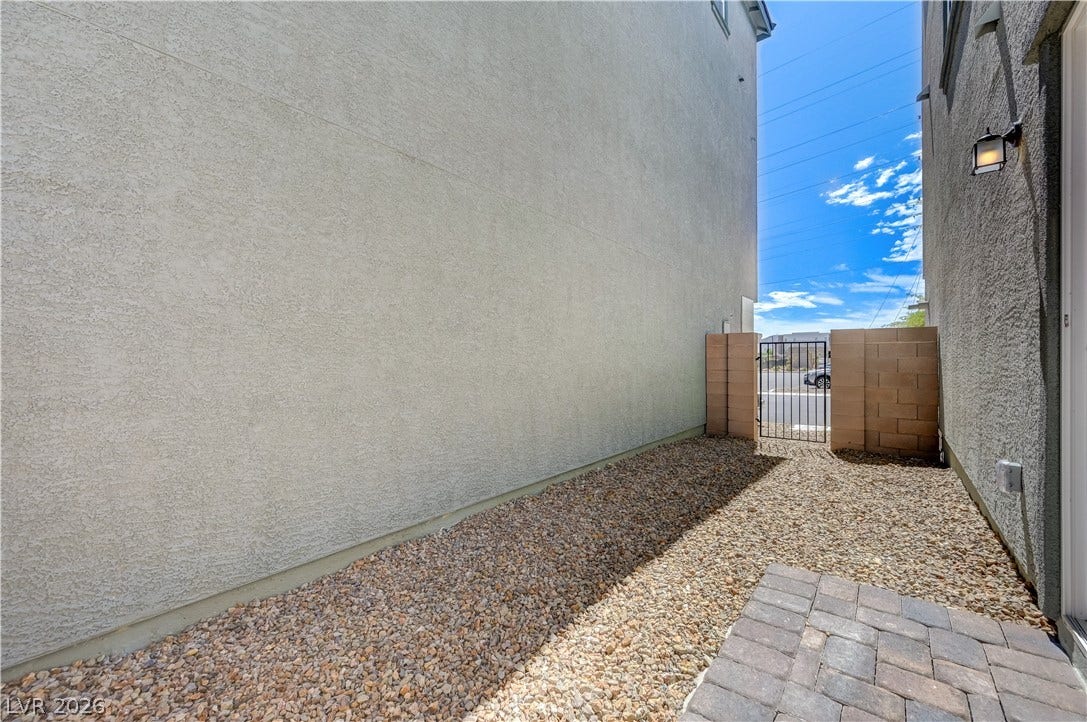 A low-maintenance gravel side yard features stucco walls and a gated entrance.