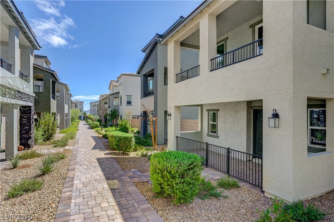 Paved pathways wind past modern multi-level exteriors featuring private balconies and covered entries.