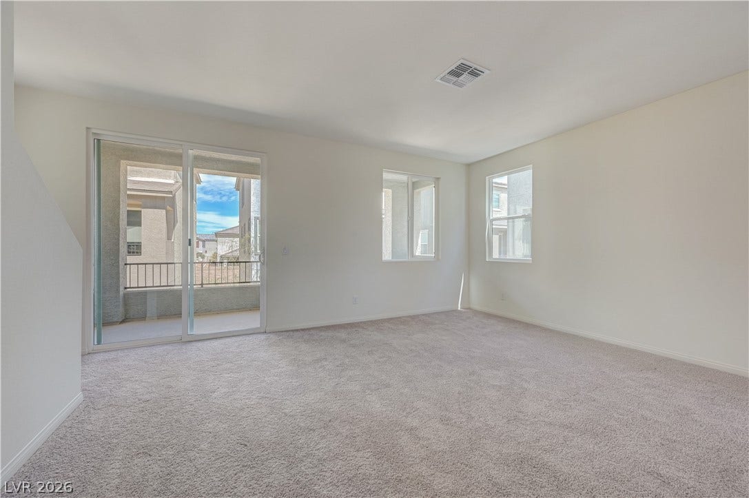 Plush carpeting and abundant natural light define this versatile living space opening to a private balcony.