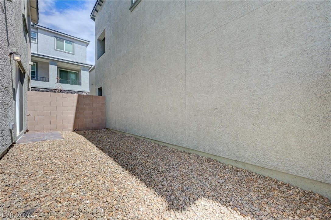 Low-maintenance gravel landscaping lines this private outdoor side yard enclosed by stucco walls.