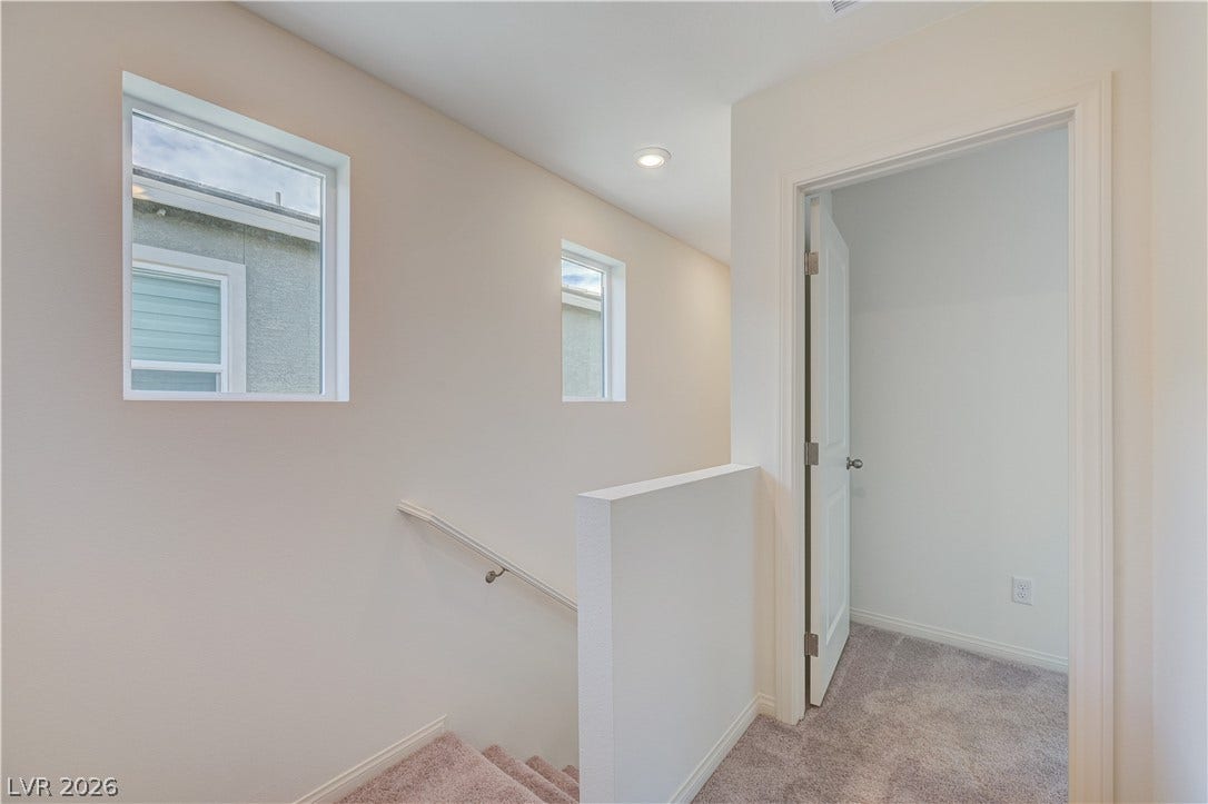 Natural light streams through high windows over the carpeted stairs and landing area.