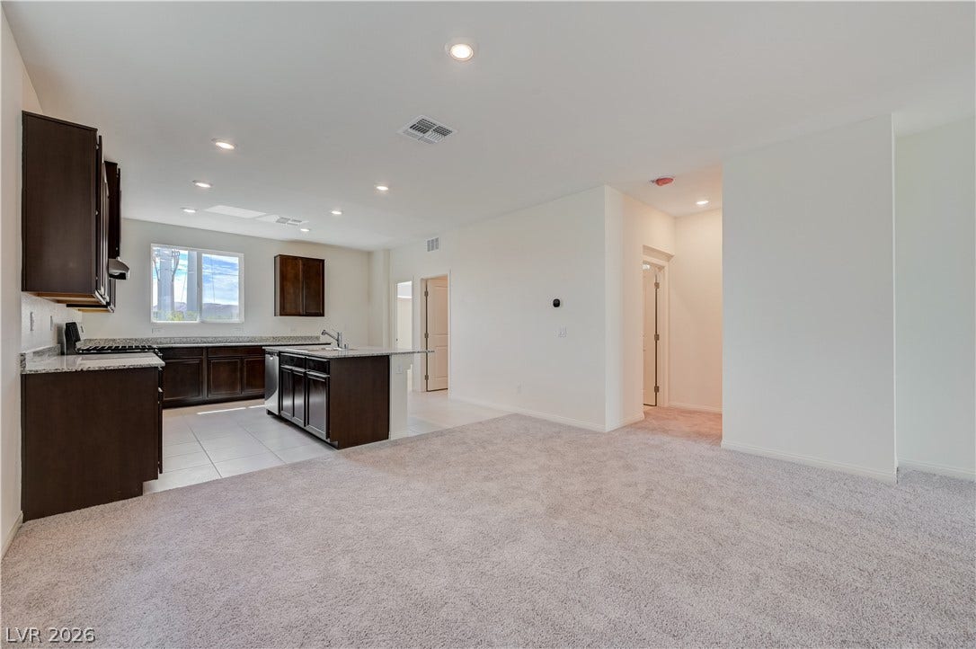 An open floorplan seamlessly connects the carpeted living area to the tiled kitchen.