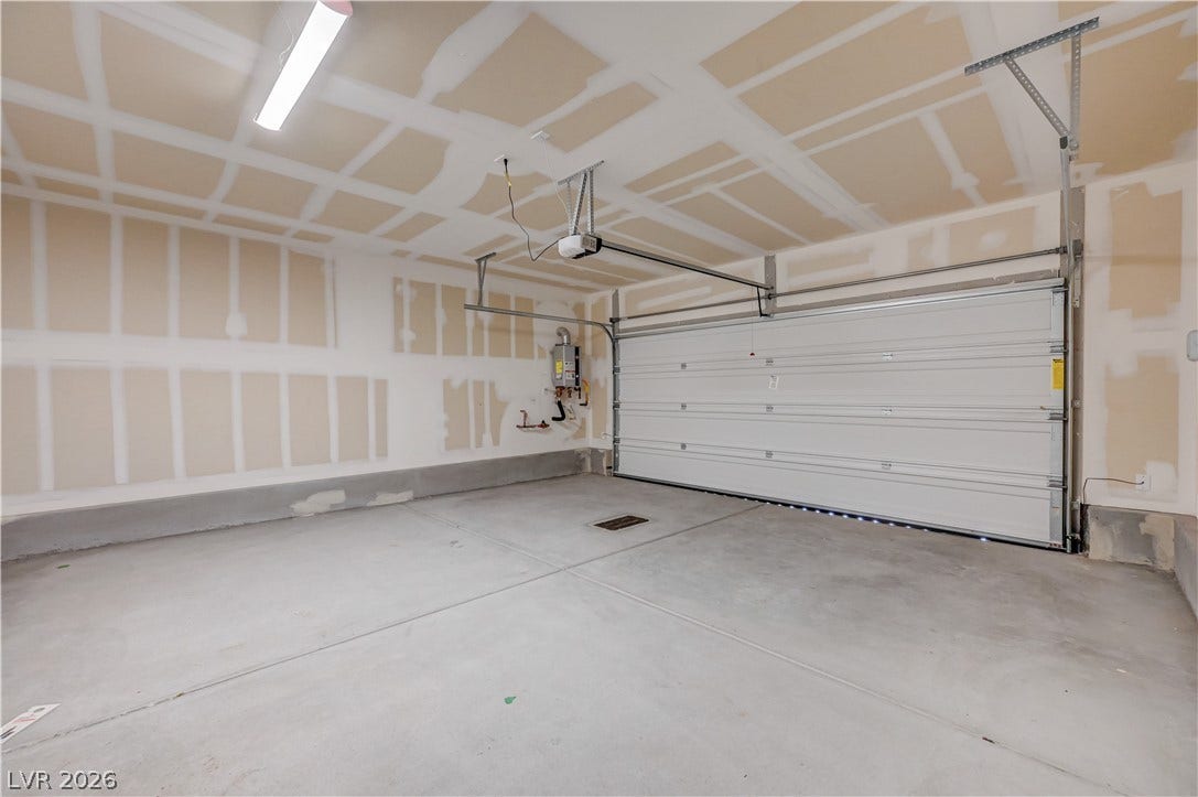 An unfinished garage features a clean concrete floor and a modern automatic overhead door.