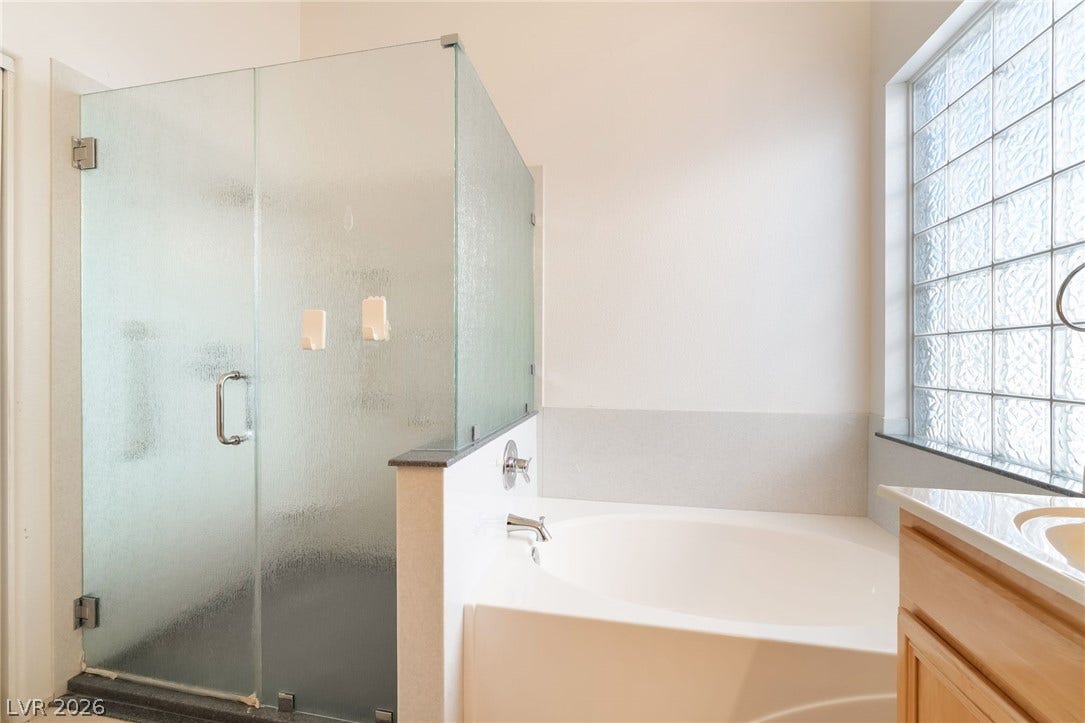 2722 Bass Lake Street, Henderson, NV 89052 A deep soaking tub sits adjacent to a glass-enclosed shower under natural light.