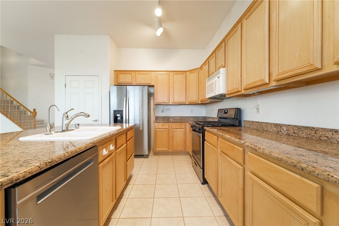 2722 Bass Lake Street, Henderson, NV 89052 Warm wood cabinetry and granite countertops frame this functional galley kitchen layout.