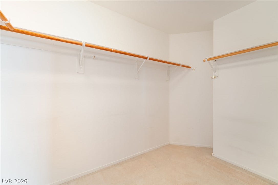 2722 Bass Lake Street, Henderson, NV 89052 Ample hanging rods and neutral carpeting define this functional walk-in closet space.