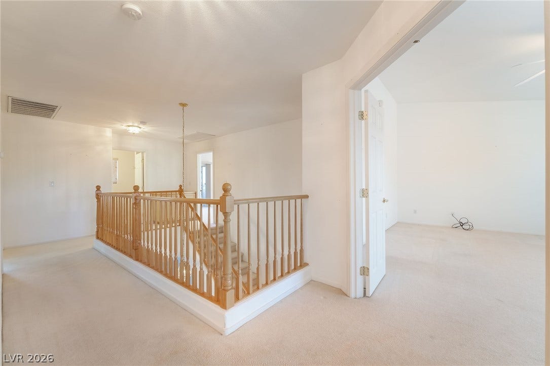 2722 Bass Lake Street, Henderson, NV 89052 An open upper level landing features carpeted flooring and wooden staircase railings.
