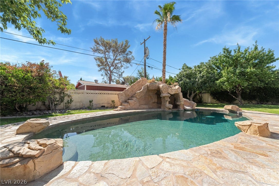 7154 Ranchito Circle, Las Vegas, NV 89120 An inviting backyard pool is bordered by natural flagstone and topped with a rock-formed slide.