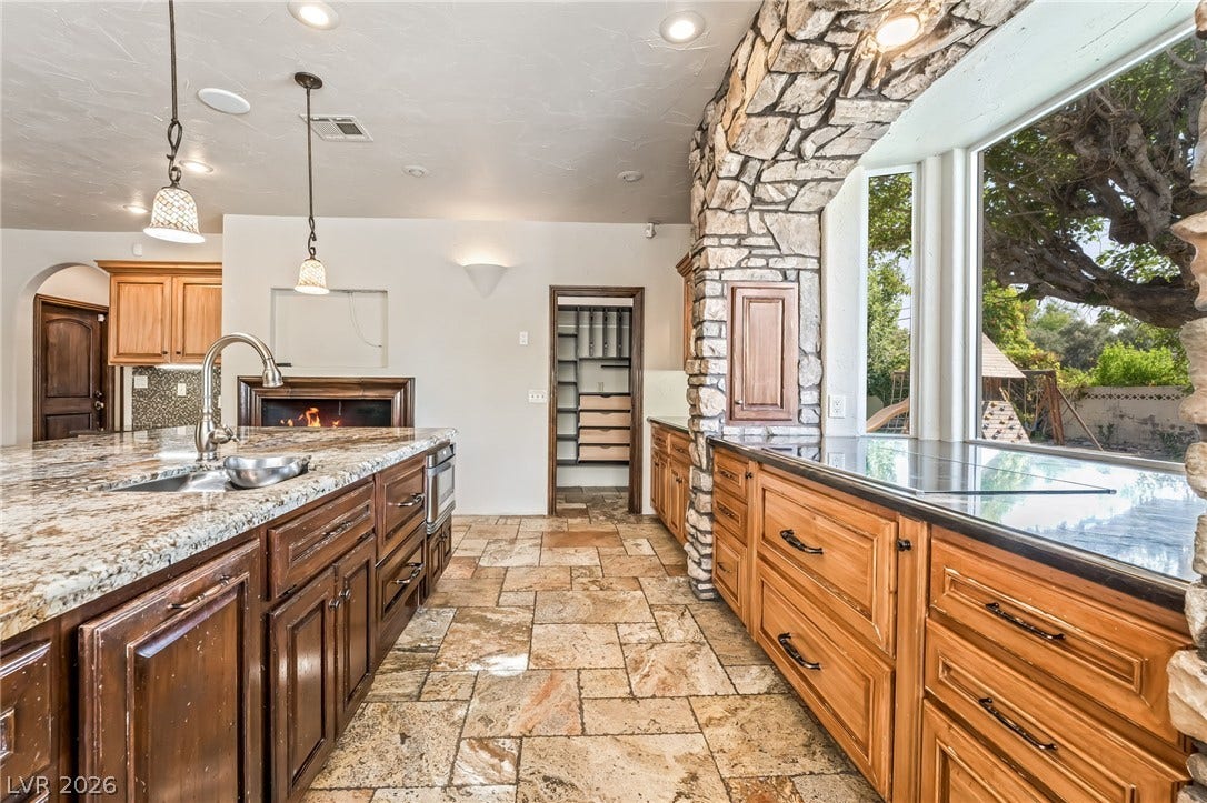 7154 Ranchito Circle, Las Vegas, NV 89120 Natural stone details frame garden views in this kitchen featuring rustic tile floors.