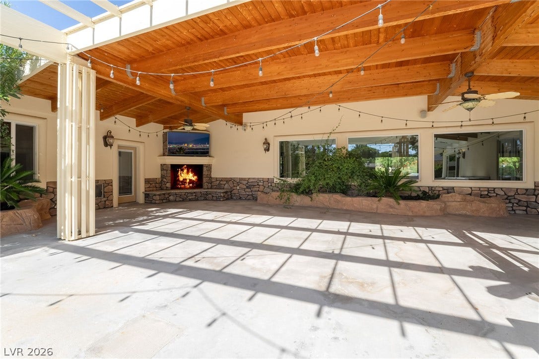 7154 Ranchito Circle, Las Vegas, NV 89120 An expansive covered patio features concrete flooring and a rustic stone fireplace.