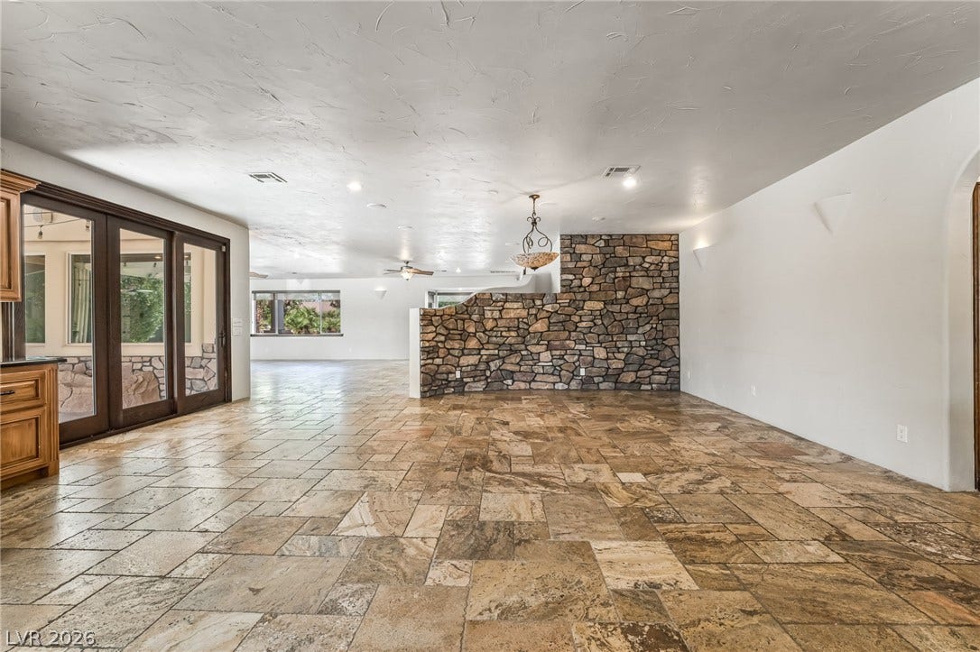 7154 Ranchito Circle, Las Vegas, NV 89120 Natural stone tile floors and a rustic stone accent wall anchor this open living area.