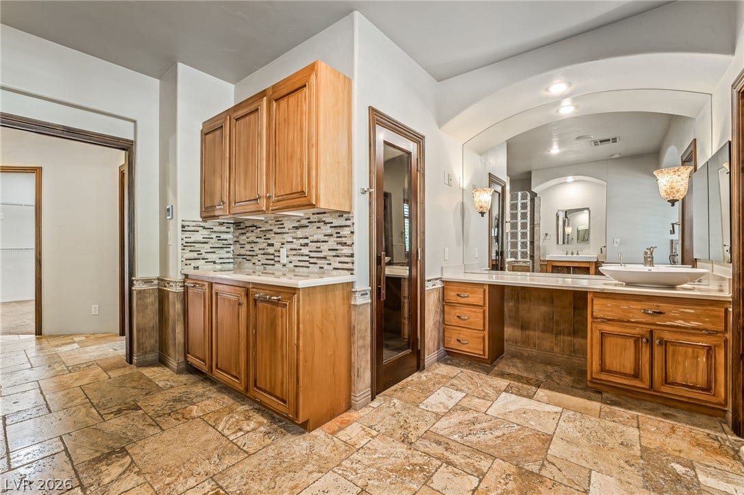 7154 Ranchito Circle, Las Vegas, NV 89120 Rich wood cabinetry and stone tile flooring create a refined atmosphere in this expansive space.