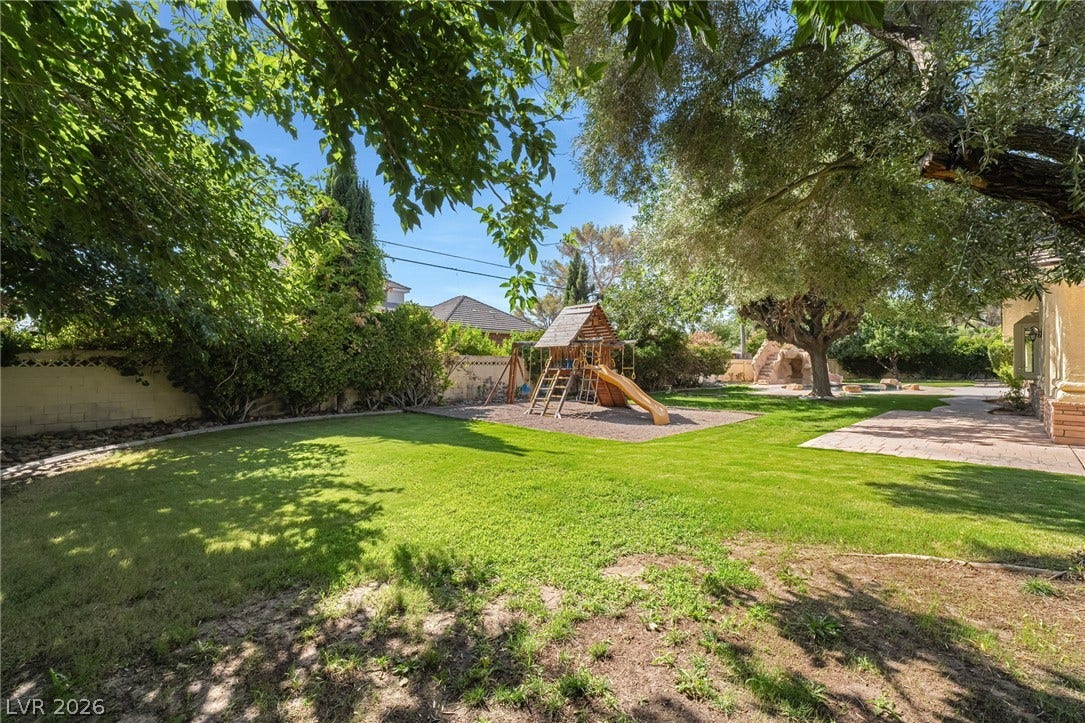 7154 Ranchito Circle, Las Vegas, NV 89120 Mature trees shade a manicured lawn featuring a dedicated play area and paved pathways.