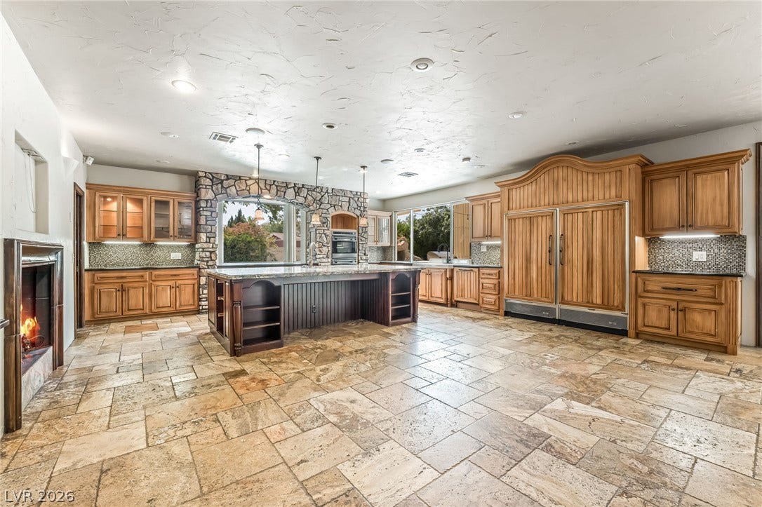 7154 Ranchito Circle, Las Vegas, NV 89120 Rich wood cabinetry and stone tile flooring anchor this grand cooking and dining space.