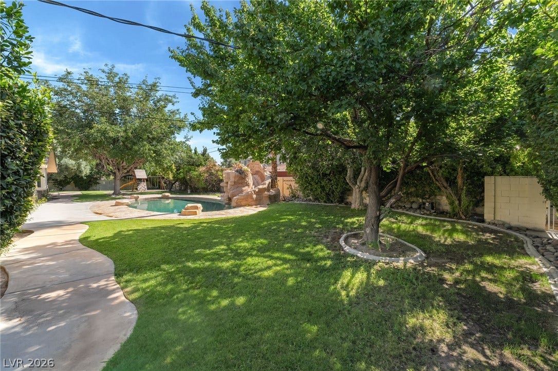 7154 Ranchito Circle, Las Vegas, NV 89120 Mature trees shade a manicured lawn alongside a winding walkway leading toward the pool.