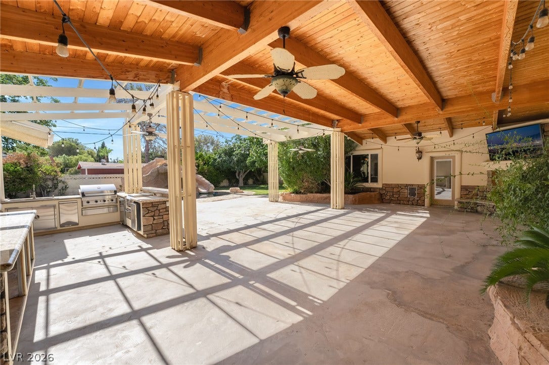 7154 Ranchito Circle, Las Vegas, NV 89120 An expansive covered patio features a fully equipped outdoor kitchen beneath a timber ceiling.