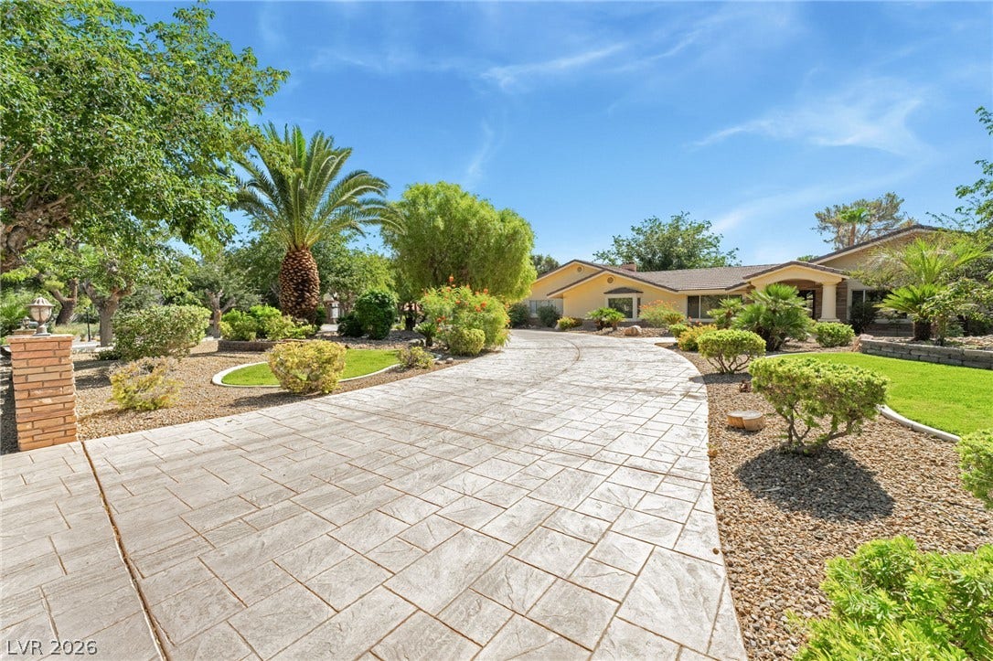 7154 Ranchito Circle, Las Vegas, NV 89120 A long stamped concrete driveway winds toward this classic single-story home amidst desert landscaping.