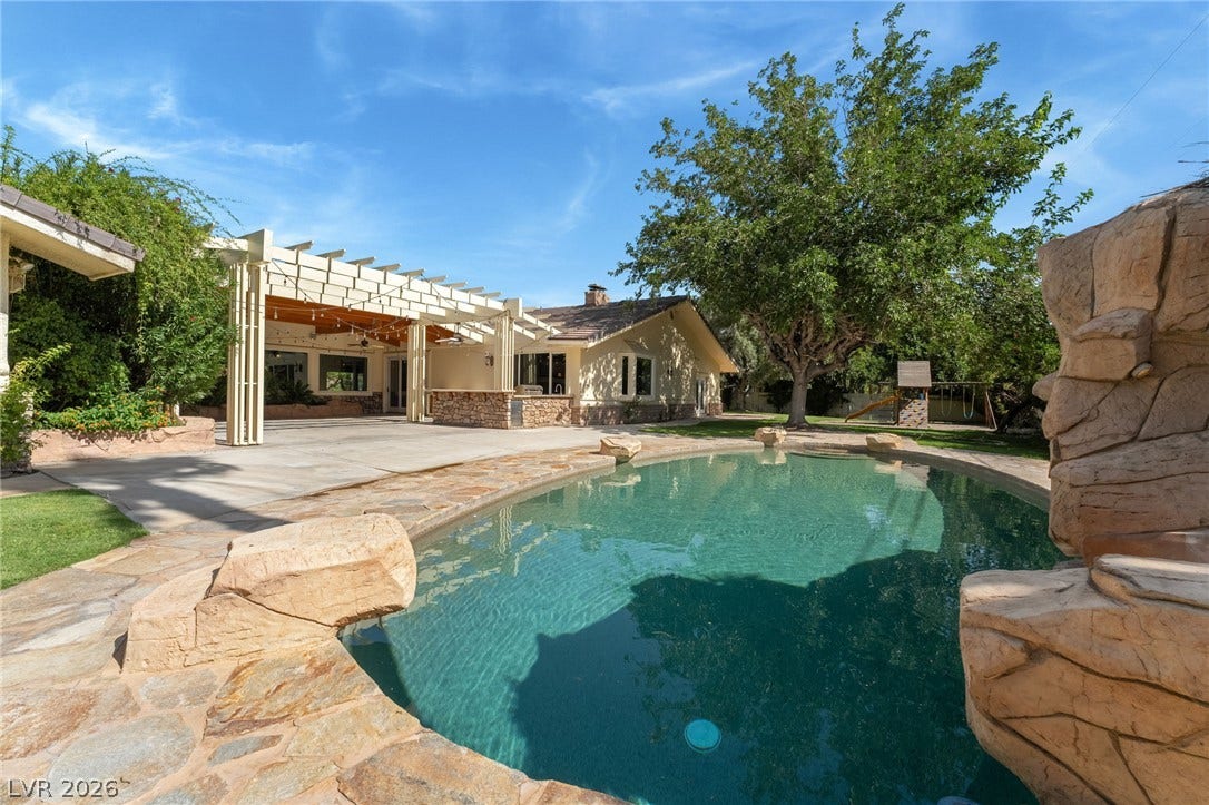 7154 Ranchito Circle, Las Vegas, NV 89120 An inviting backyard oasis features a rock-rimmed pool alongside a spacious covered patio.