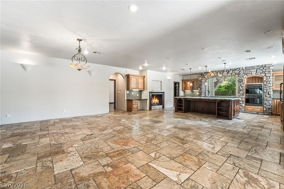 7154 Ranchito Circle, Las Vegas, NV 89120 Earth-toned stone tile floors and a rustic stone fireplace accent this expansive open interior.