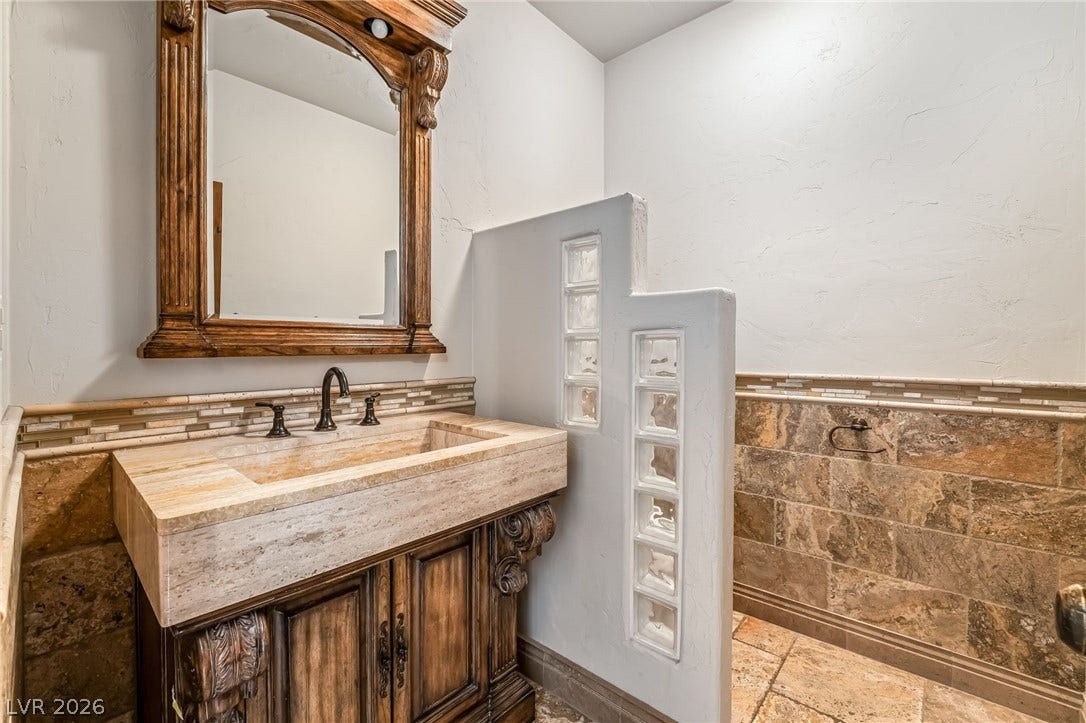 7154 Ranchito Circle, Las Vegas, NV 89120 Ornate woodwork and rustic stone tiles elevate this bathroom with character.