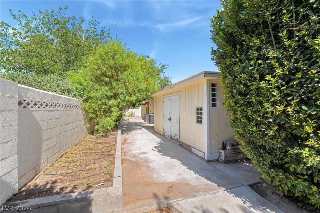 7154 Ranchito Circle, Las Vegas, NV 89120 An outdoor utility area features a paved walkway alongside a block privacy wall and garden beds.
