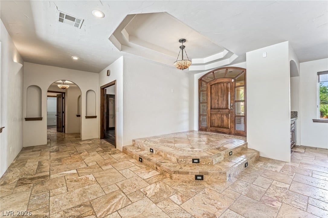7154 Ranchito Circle, Las Vegas, NV 89120 An elegant recessed entryway welcomes guests with tiered stone tile steps and a carved wood door.