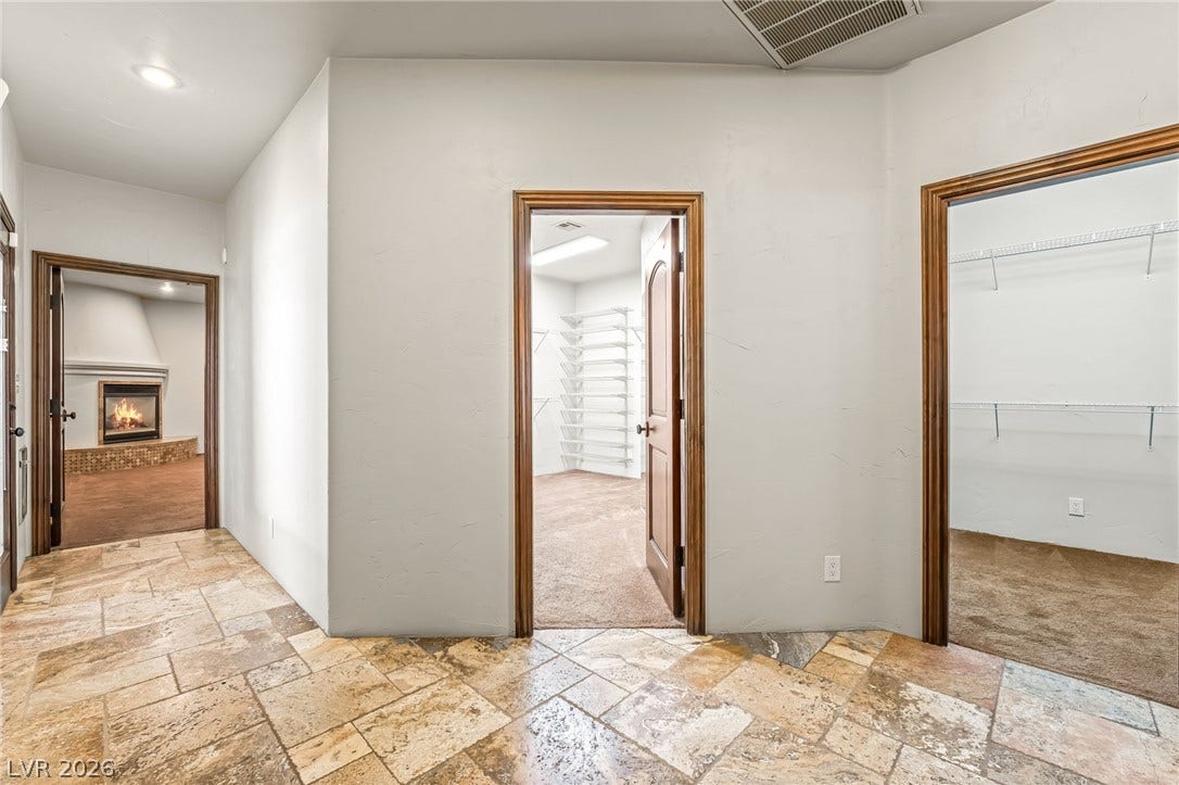 7154 Ranchito Circle, Las Vegas, NV 89120 Stone tile flooring leads to multiple closets and a nearby room with a fireplace.