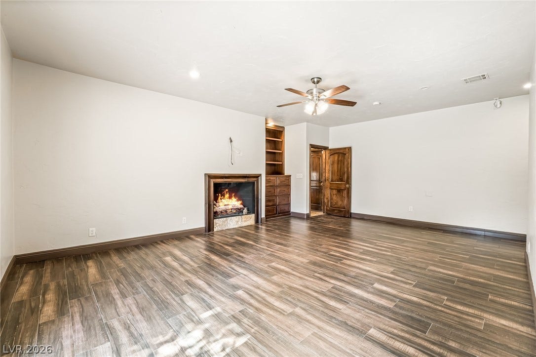 7154 Ranchito Circle, Las Vegas, NV 89120 A comforting fireplace anchors this expansive living space lined with rich wood-look flooring.