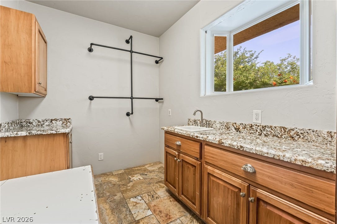7154 Ranchito Circle, Las Vegas, NV 89120 Natural stone counters and warm wood cabinetry define this functional utility space.
