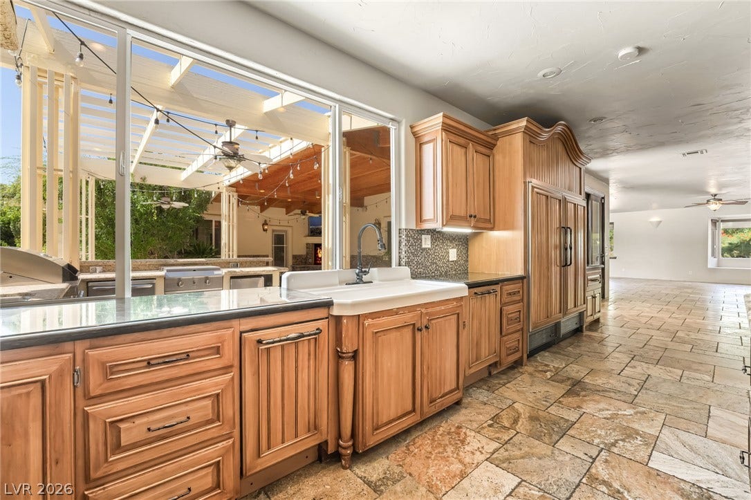7154 Ranchito Circle, Las Vegas, NV 89120 Gleaming stone tile flooring and warm wood cabinetry define this expansive culinary preparation space.