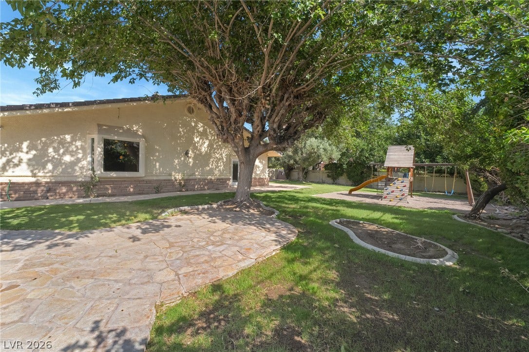 7154 Ranchito Circle, Las Vegas, NV 89120 Mature trees shade a spacious lawn featuring stone pathways and a built-in play structures.