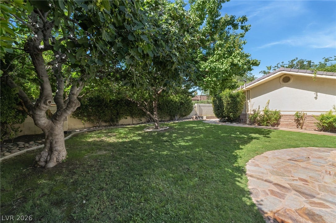 7154 Ranchito Circle, Las Vegas, NV 89120 Mature trees shade a manicured lawn alongside a stone patio.