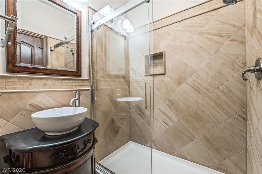 7154 Ranchito Circle, Las Vegas, NV 89120 Elegant tile work and a glass shower surround define this modern bathroom space.