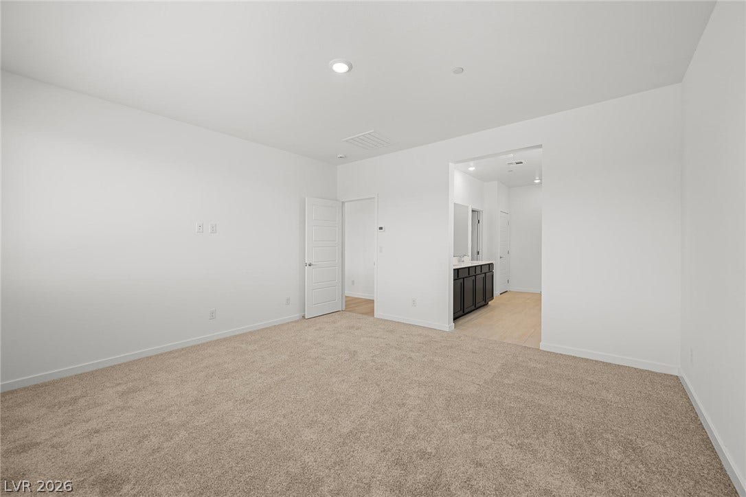 1670 Capri Falls Court, Henderson, NV 89011 An open doorway connects this carpeted bedroom directly to the adjacent bathroom.