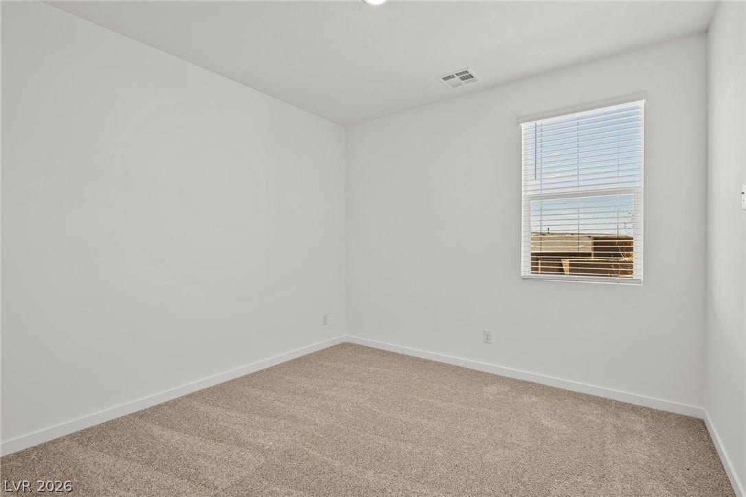 1670 Capri Falls Court, Henderson, NV 89011 A window overlooks the exterior from this quiet bedroom featuring neutral carpet flooring.