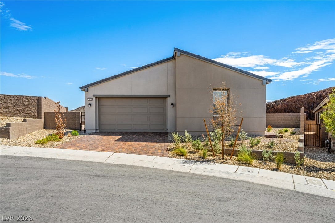 1670 Capri Falls Court, Henderson, NV 89011 A paved paver driveway leads to a modern stucco facade under clear desert skies.
