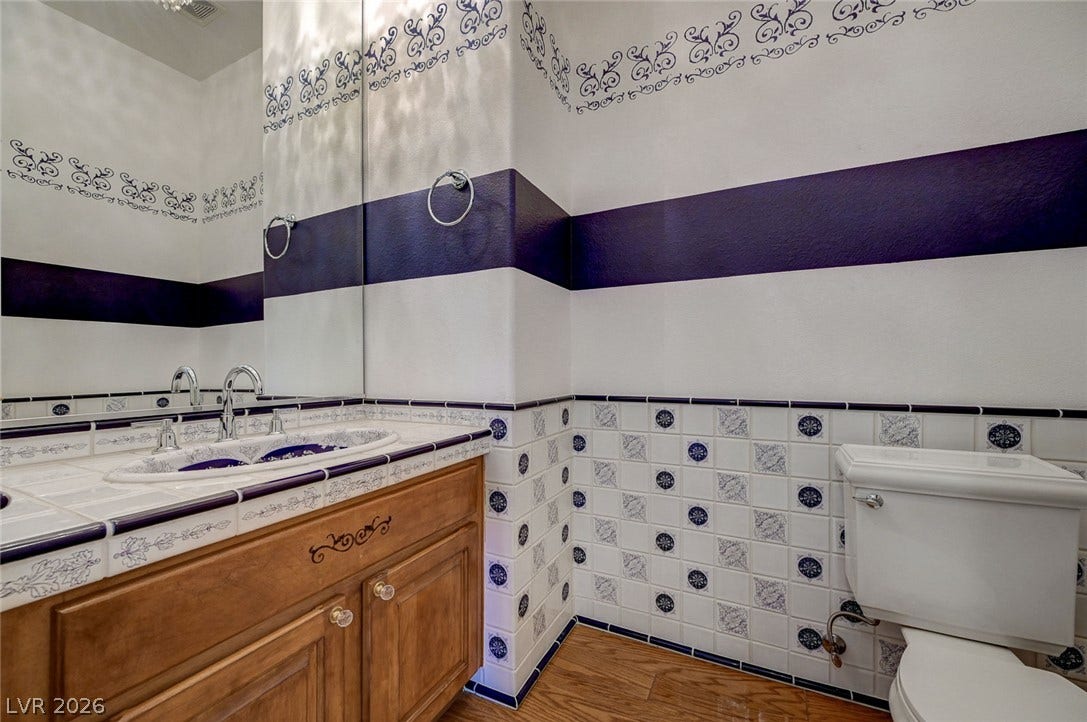 8 Starbrook Drive, Henderson, NV 89052 Ornate tile wainscoting and natural wood cabinetry define this charming restroom space.