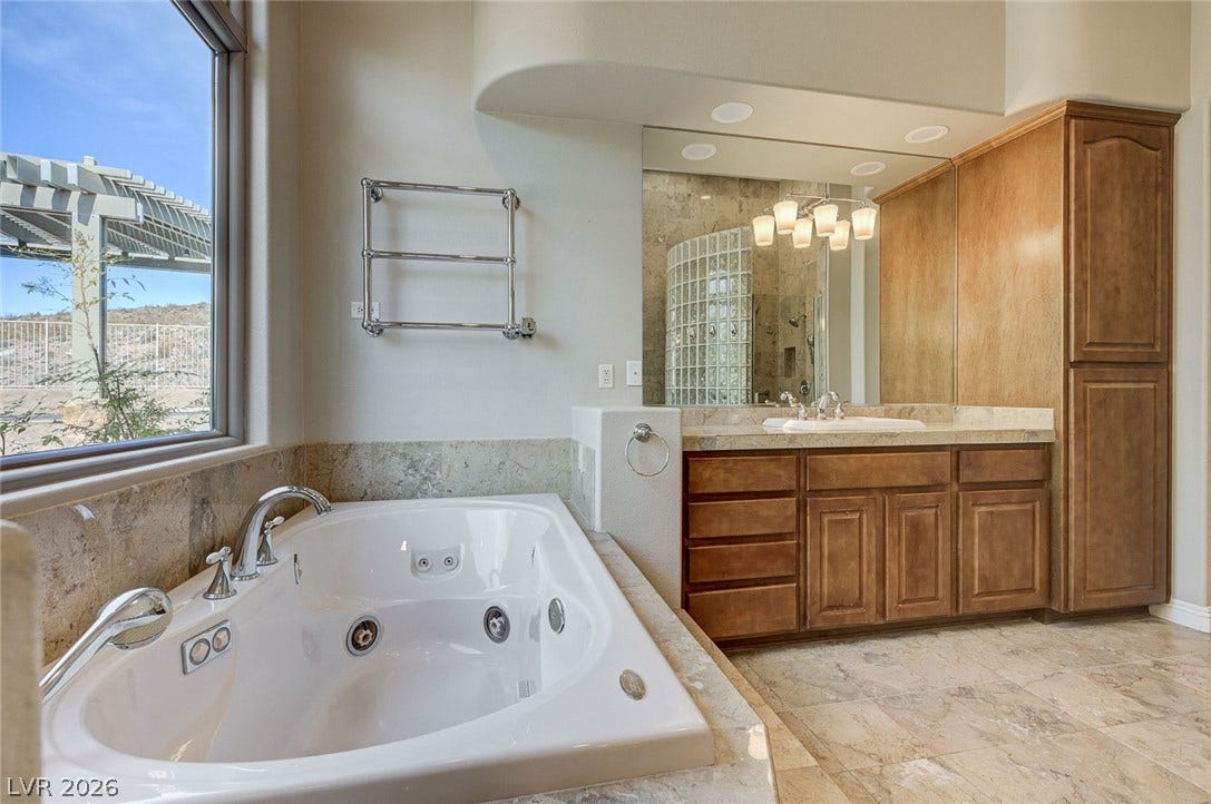 8 Starbrook Drive, Henderson, NV 89052 Natural stone tile floors and a built-in soaking tub define this elegant bathroom retreat.