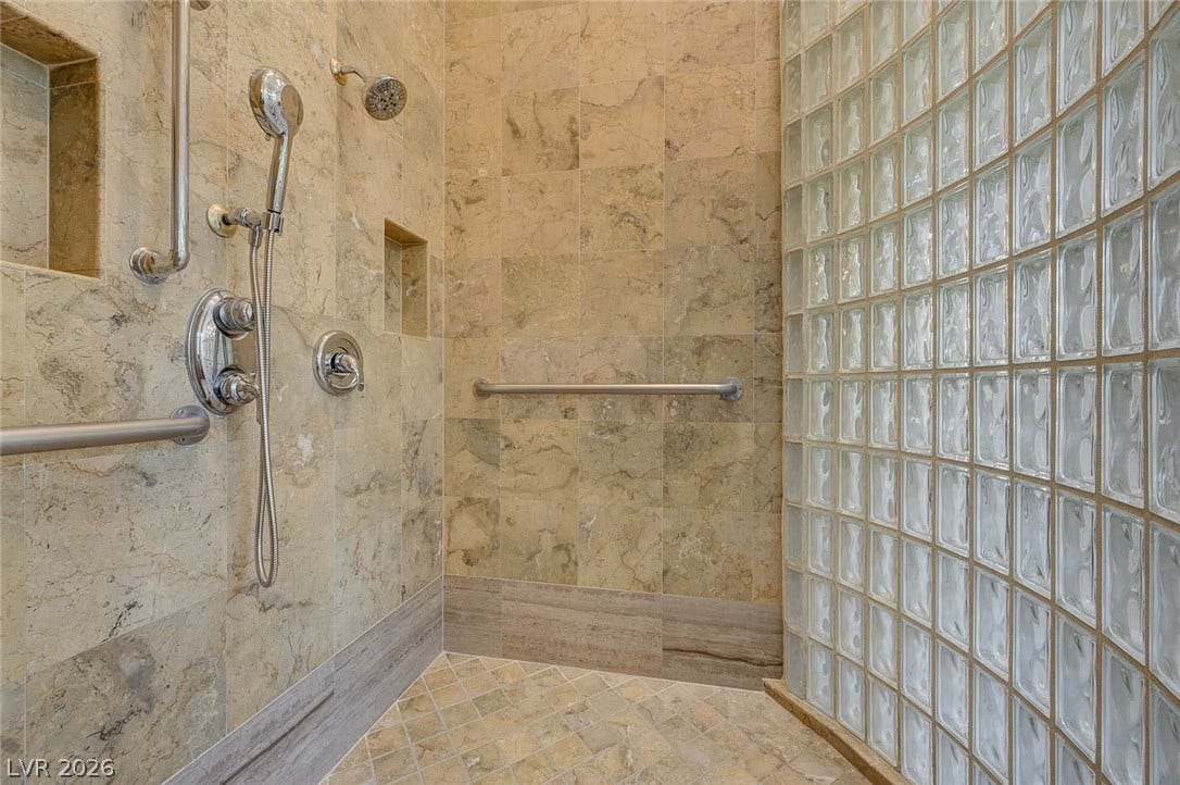 8 Starbrook Drive, Henderson, NV 89052 Natural stone tiles line the walls of a spacious walk-in shower featuring a glass-block wall.