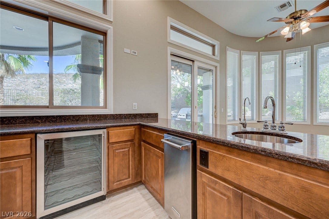 8 Starbrook Drive, Henderson, NV 89052 Rich granite countertops and custom wood cabinetry define this functional wet bar and ice frig area.