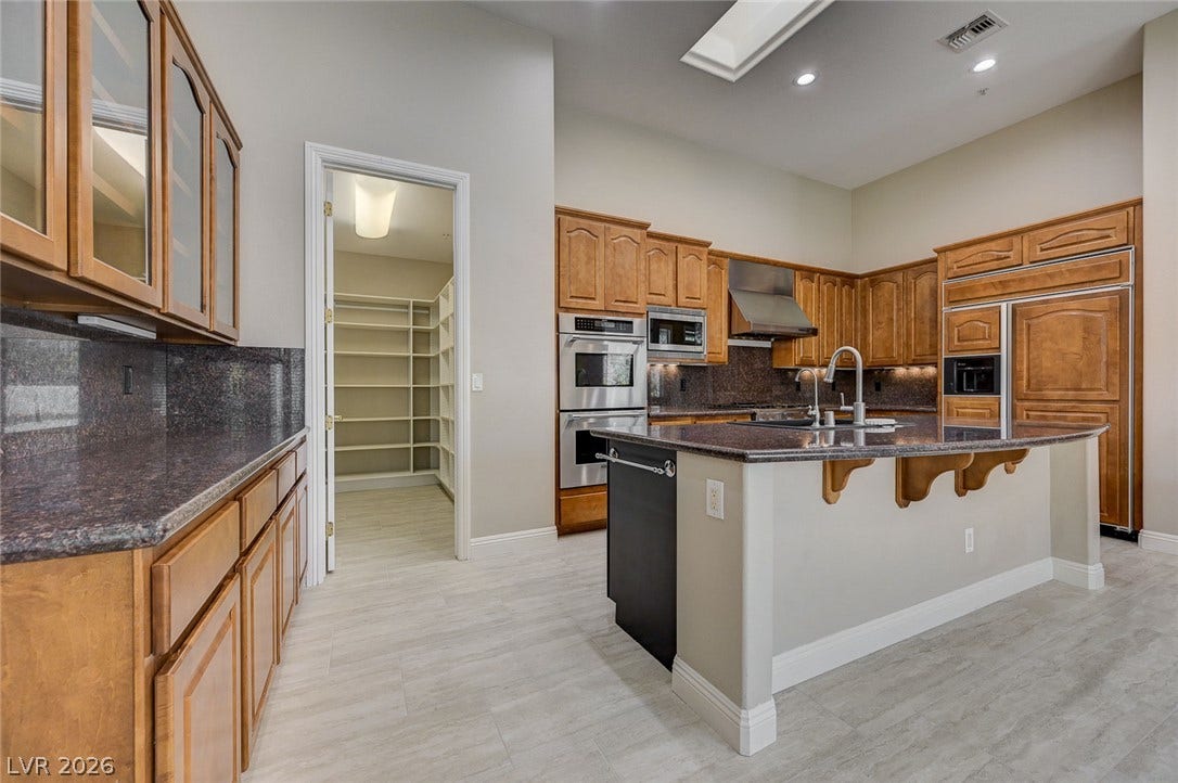 8 Starbrook Drive, Henderson, NV 89052 Gleaming stone countertops and classic wood cabinetry define this kitchen featuring a walk-in pantry.