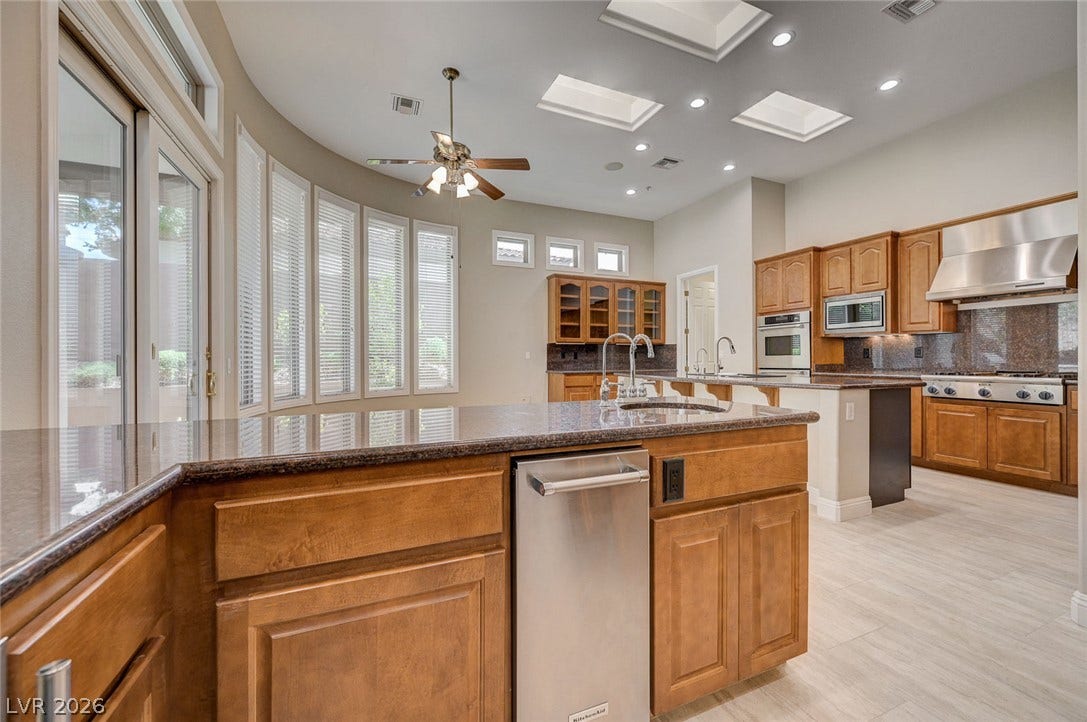 8 Starbrook Drive, Henderson, NV 89052 Polished stone counters, custom cabinetry, and skylights elevate this spacious, light-filled culinary space.
