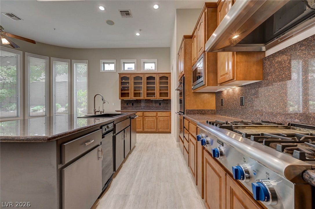 8 Starbrook Drive, Henderson, NV 89052 Rich wood cabinetry and expansive granite countertops define this well-appointed gourmet workspace.