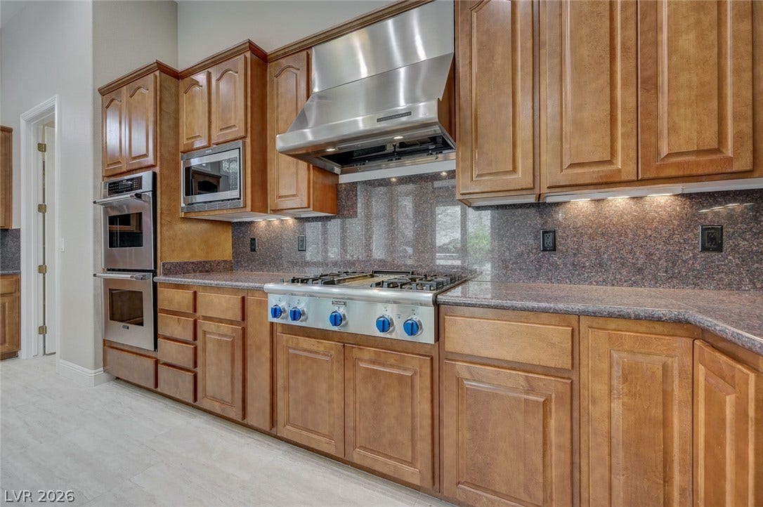 8 Starbrook Drive, Henderson, NV 89052 Gleaming stone countertops and classic wood cabinetry line this modern kitchen space.