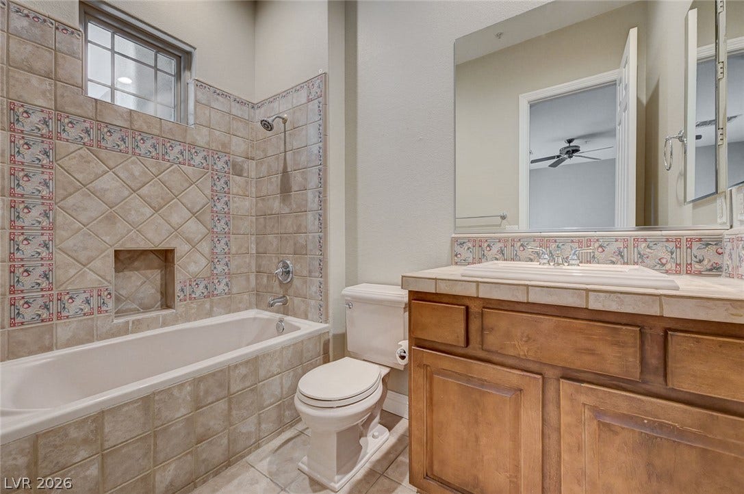8 Starbrook Drive, Henderson, NV 89052 Decorative wall tiling surrounds the built-in bathtub adjacent to a classic wood vanity.
